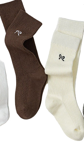 Three pairs of socks in brown, white, and beige on a light gray background