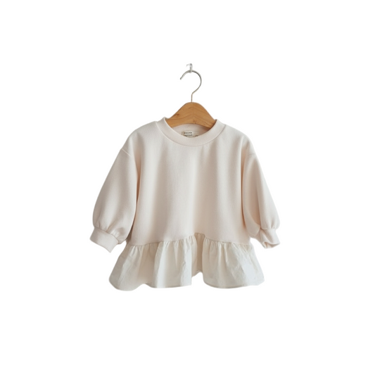 Beige sweater with ruffled hem on a wooden hanger against a white background