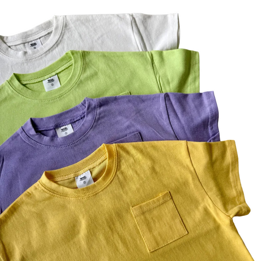 Four t-shirts in yellow, purple, green, and white on a neutral background