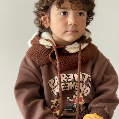 Child wearing a brown hoodie with text and graphics on a plain background