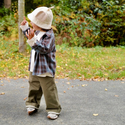 Two children playing outdoors on a path with trees and grass in the background